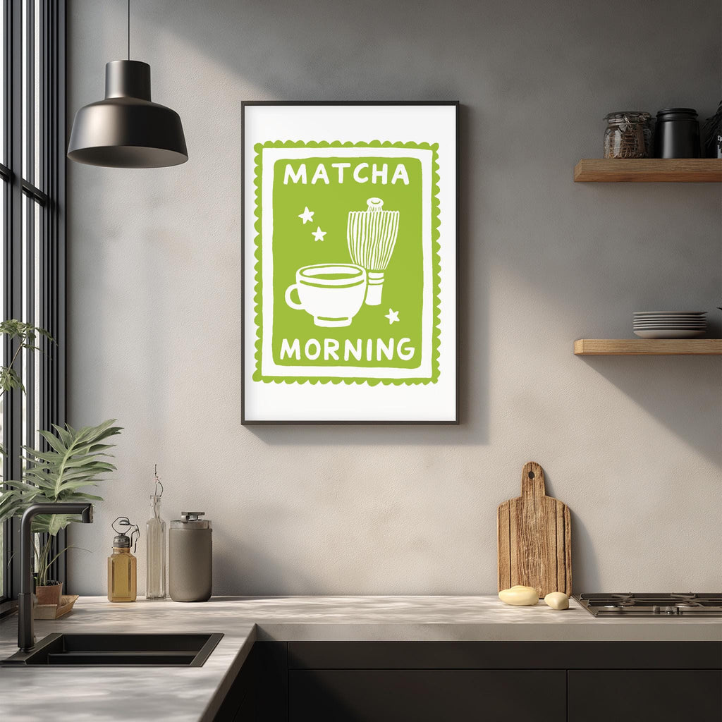 a kitchen counter with various kitchen items, including a framed poster with a green border and white text that reads "MATCHA MORNING".