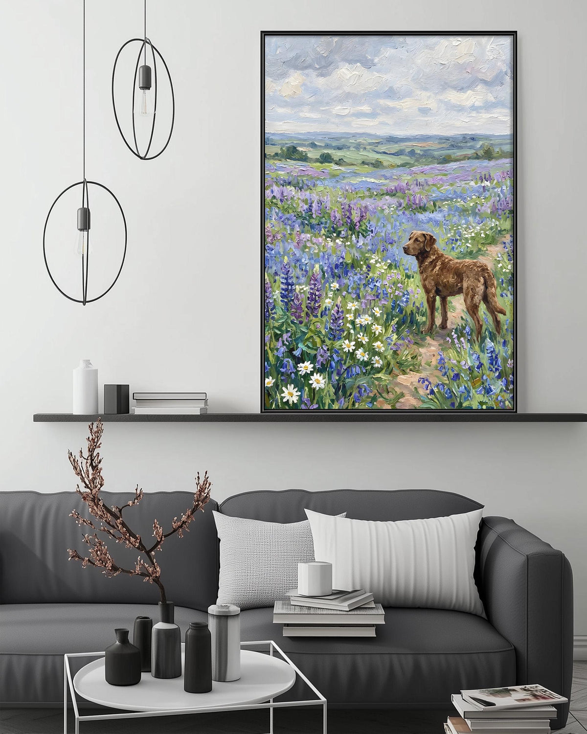 a large painting of a dog standing in a field of flowers, with a serene landscape in the background. The painting is hung on a wall above a gray couch, which has a coffee table in front of it. The room also includes a shelf with decorative items and a potted plant.