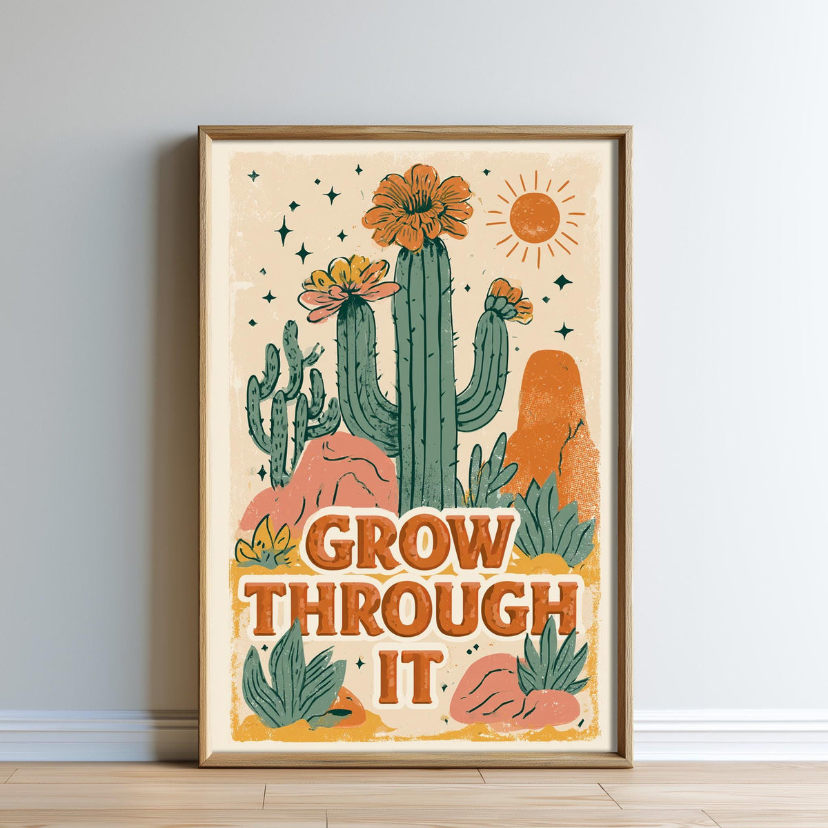 The image is a framed poster with a desert-themed illustration featuring cacti, flowers, and a sun. The poster has the text "Grow Through It" written on it.