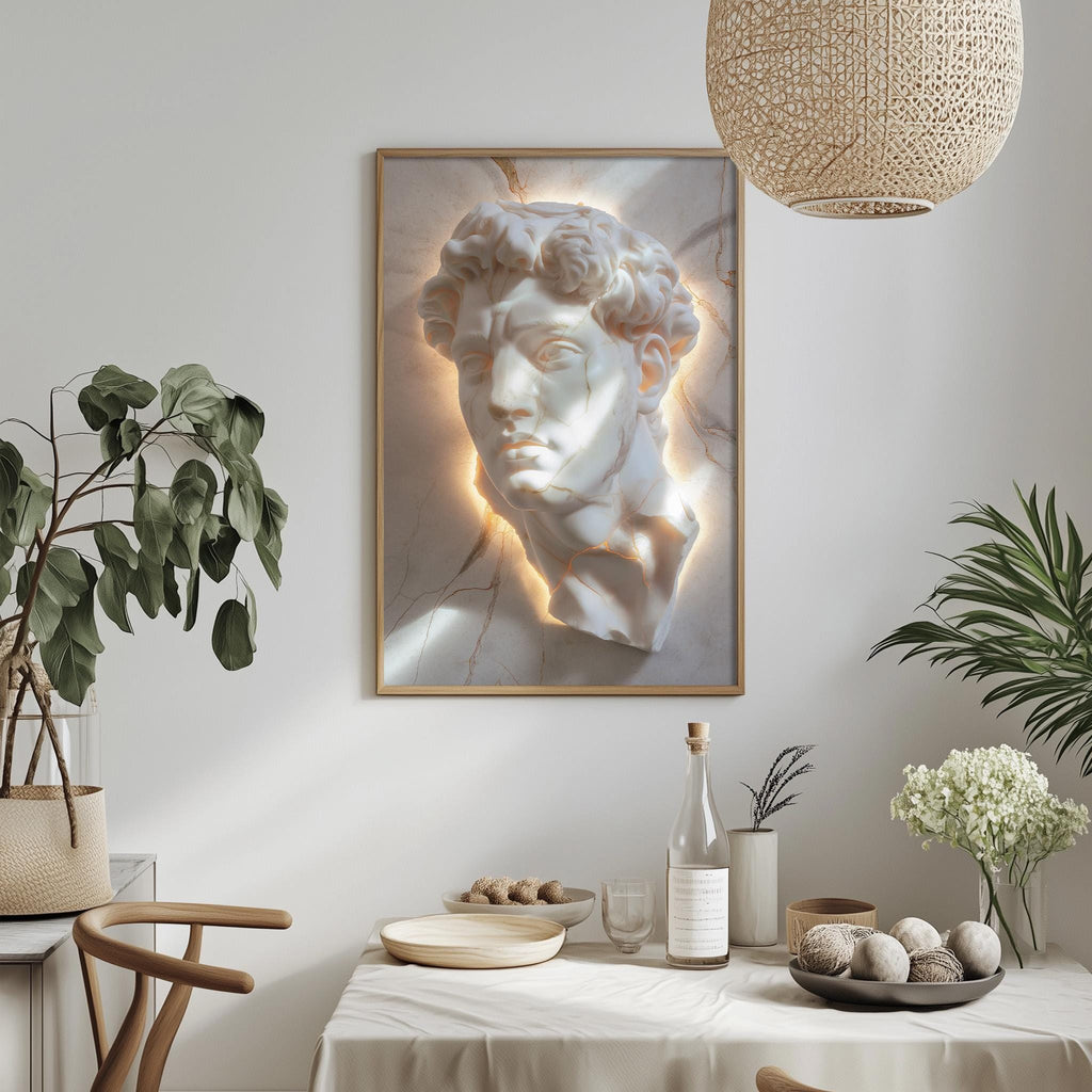 a dining table with a white tablecloth, a bowl of fruit, a bottle, and a vase with flowers. Above the table, there is a framed image of a marble bust of a man's face.