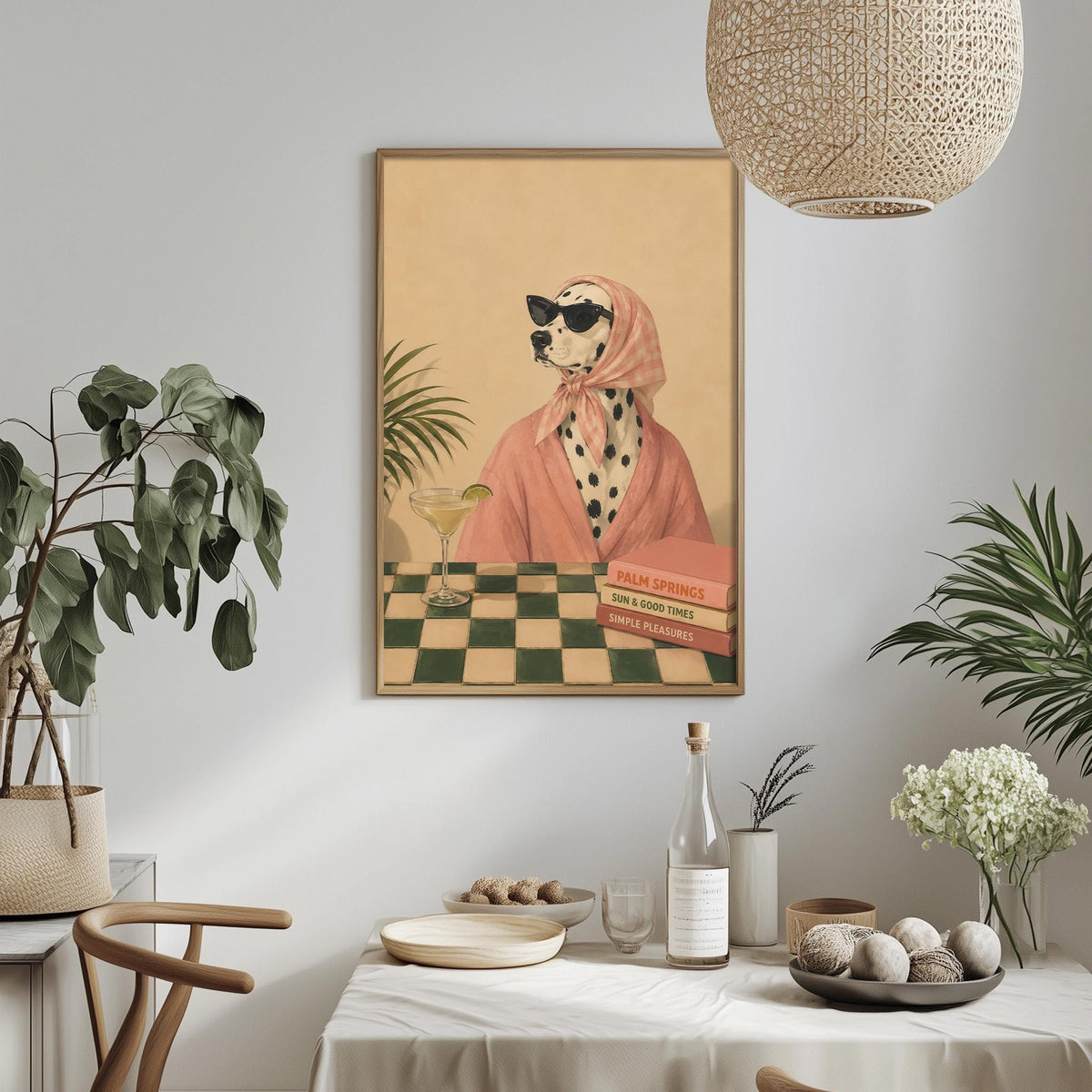 a framed painting of a Dalmatian dog wearing a pink robe and sunglasses, sitting at a table with a checkered tablecloth, surrounded by potted plants and a bottle of wine.