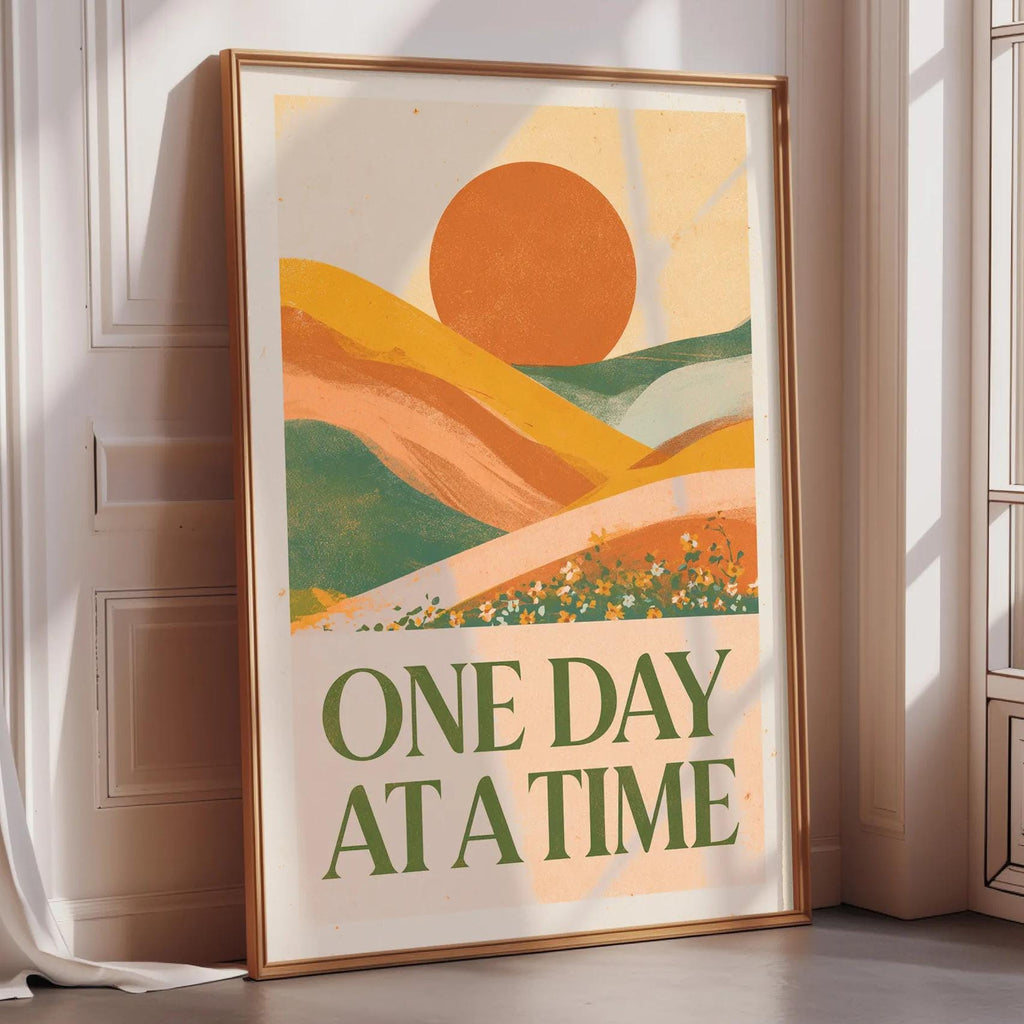 a framed poster with a vibrant, abstract landscape design and the text "ONE DAY AT A TIME" displayed prominently on it.