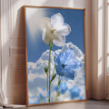 A framed photograph of two white and blue flowers against a backdrop of a blue sky with fluffy white clouds.