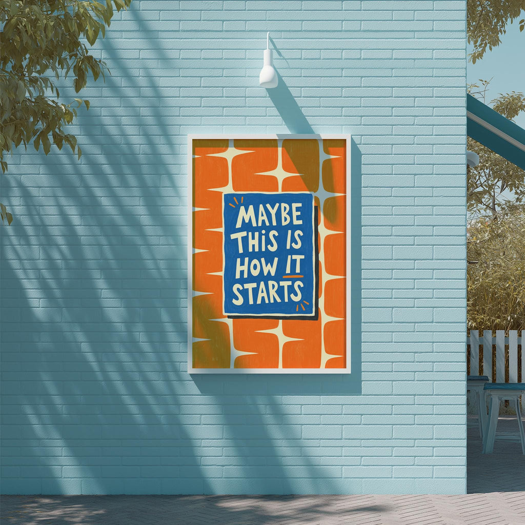 a blue wall with a framed poster that reads "MAYBE THIS IS HOW IT STARTS" in white text.