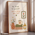 The image is a framed poster with a motivational message encouraging the viewer to be kind to themselves and focus on doing their best. The poster includes illustrations of a vase with flowers, a cup of coffee, and a candle, along with the text "be kind to yourself, you're doing your best" and "take it slow, good things take time".