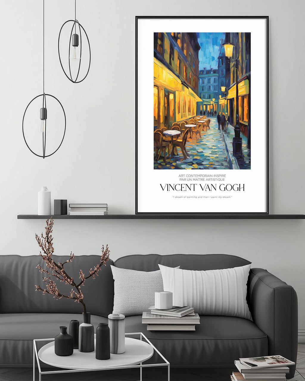 a large framed painting of a street scene with a building and a person walking, hanging on a wall above a gray couch with a coffee table in front of it.
