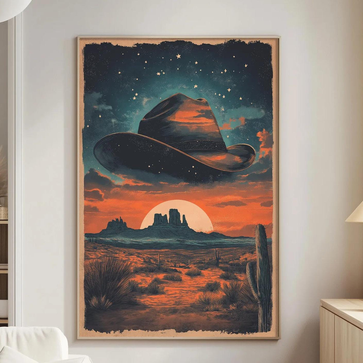 a large framed poster of a desert landscape with a cowboy hat in the sky, depicting a sunset over a desert scene.