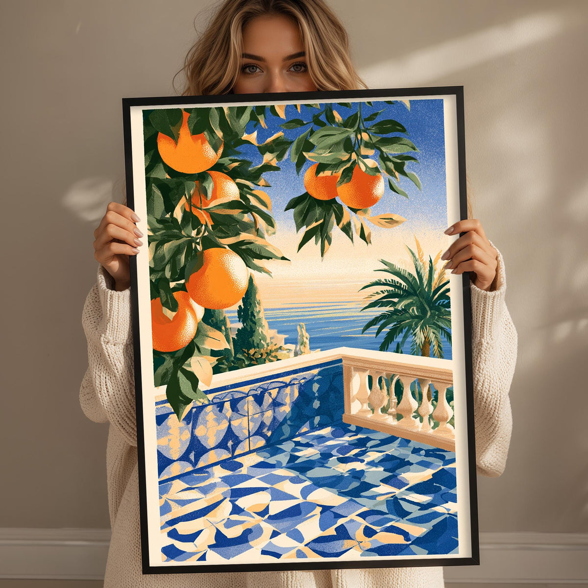 A woman holds up a framed painting depicting a balcony with a tiled floor and a palm tree, overlooking the ocean.