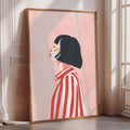 a framed illustration of a woman with short black hair wearing a red and white striped shirt.