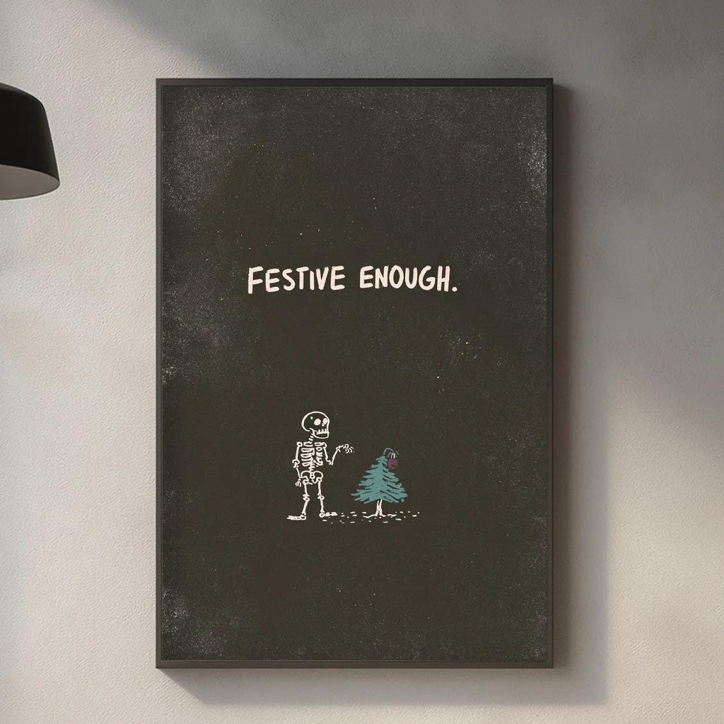 a kitchen counter with various items such as a cutting board, a plant, and a bottle. Above the counter, there is a framed poster with the text "FESTIVE EOUGH" and an illustration of a skeleton and a Christmas tree.