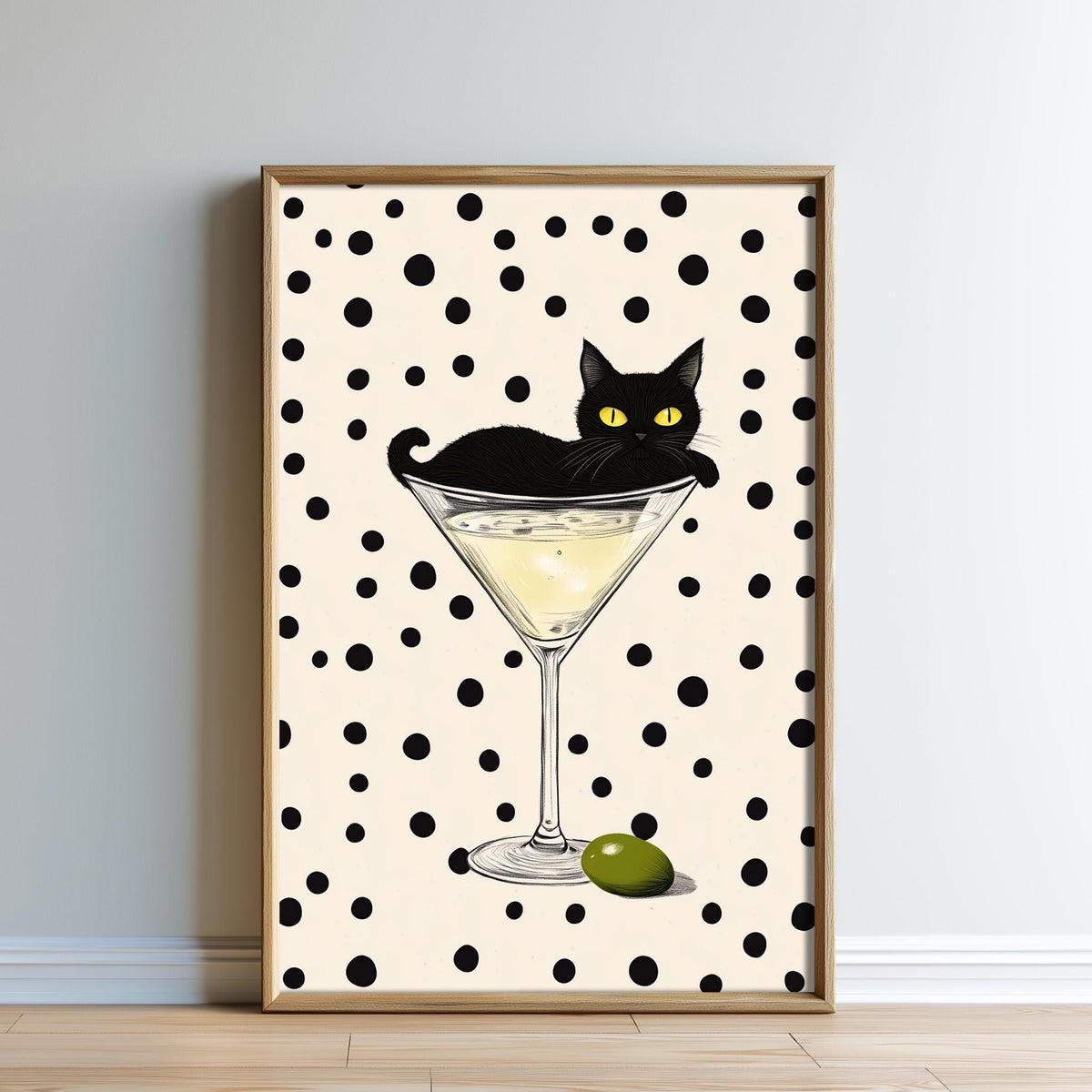 A framed illustration of a black cat sitting on a martini glass, with a green olive on the rim of the glass.