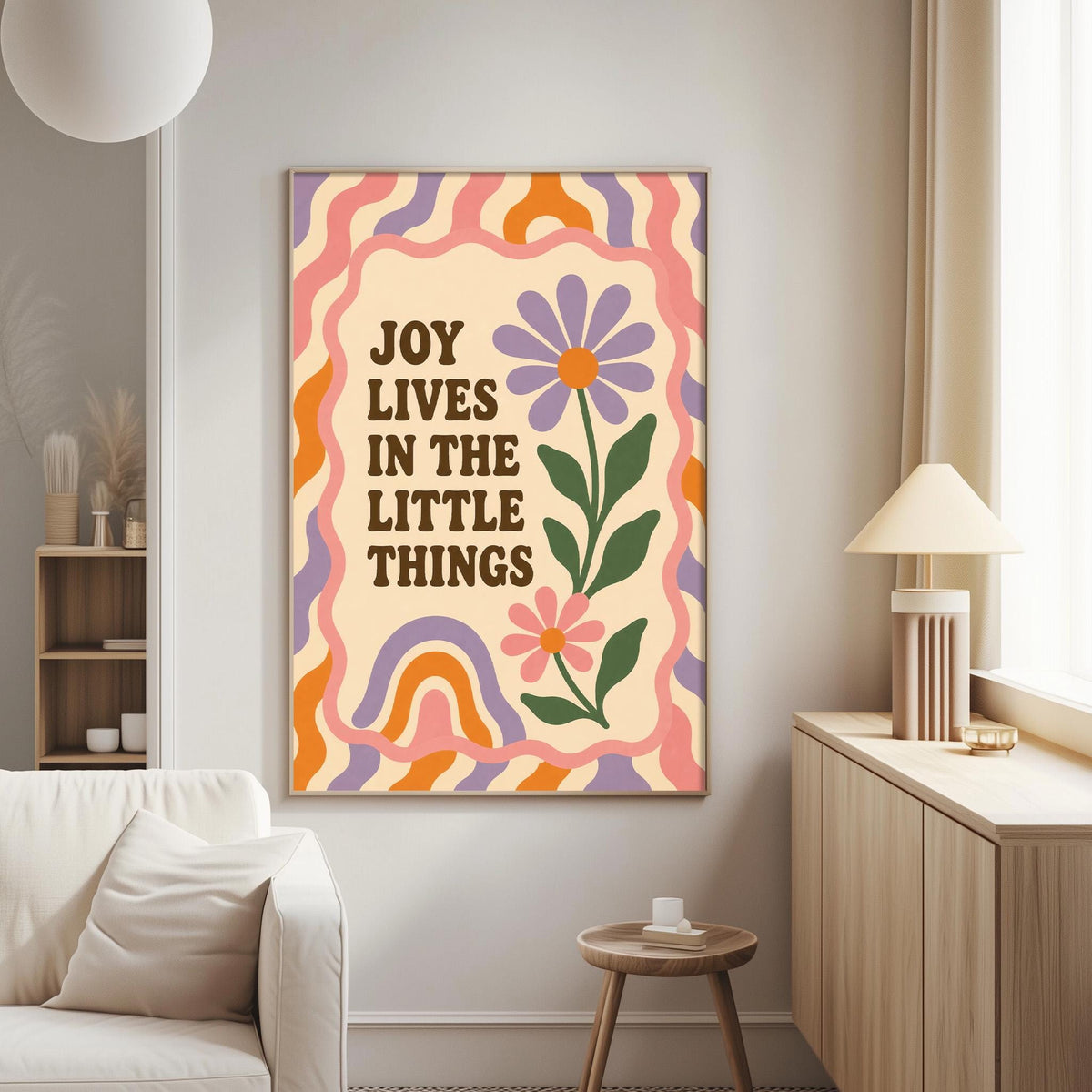 a poster with a floral design and the text "Joy lives in the little things" hanging on a wall in a living room.