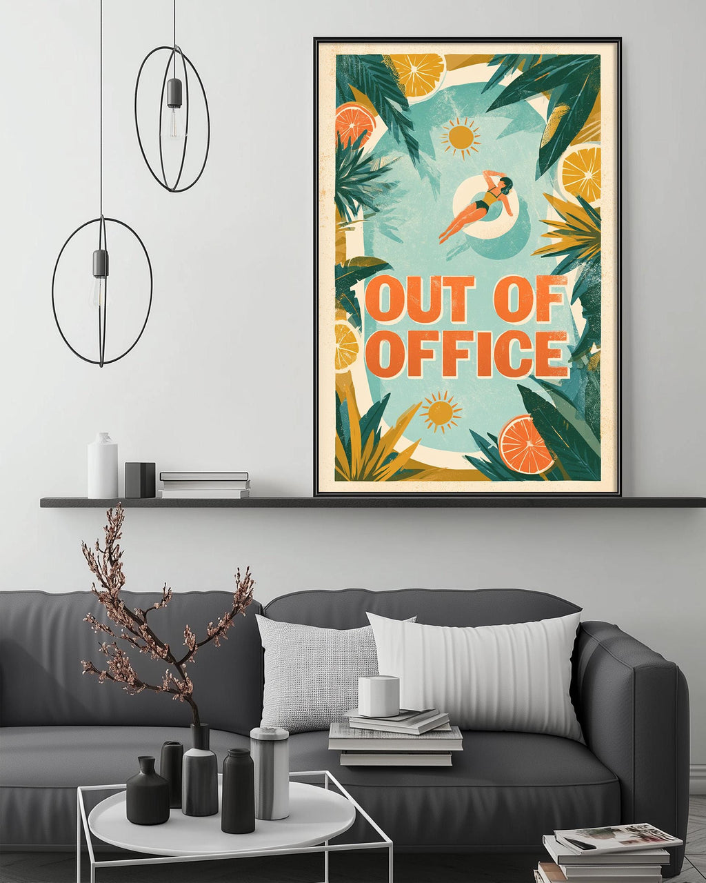 a living room with a gray couch, a coffee table, and a framed poster hanging on the wall. The poster has a tropical design with a woman swimming in a pool surrounded by palm trees and oranges.