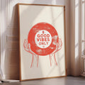 A framed poster with a red vinyl record design and the text "GOOD VIBES ONLY" is displayed on a wall.