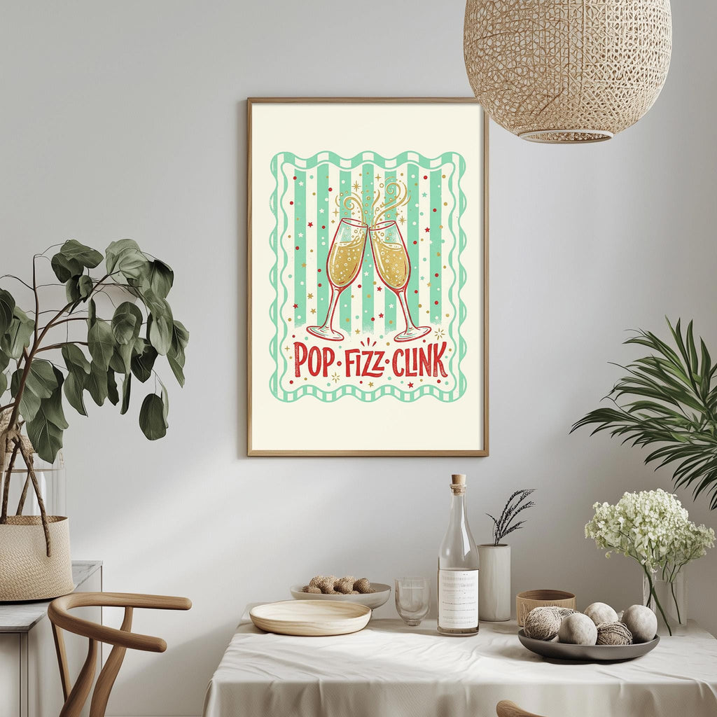 a framed poster with a design of two champagne glasses and the text "POP-FIZZ-CLINK" on a white background. The poster is hanging on a wall above a dining table with various decorative items, including potted plants, vases, and a bowl.