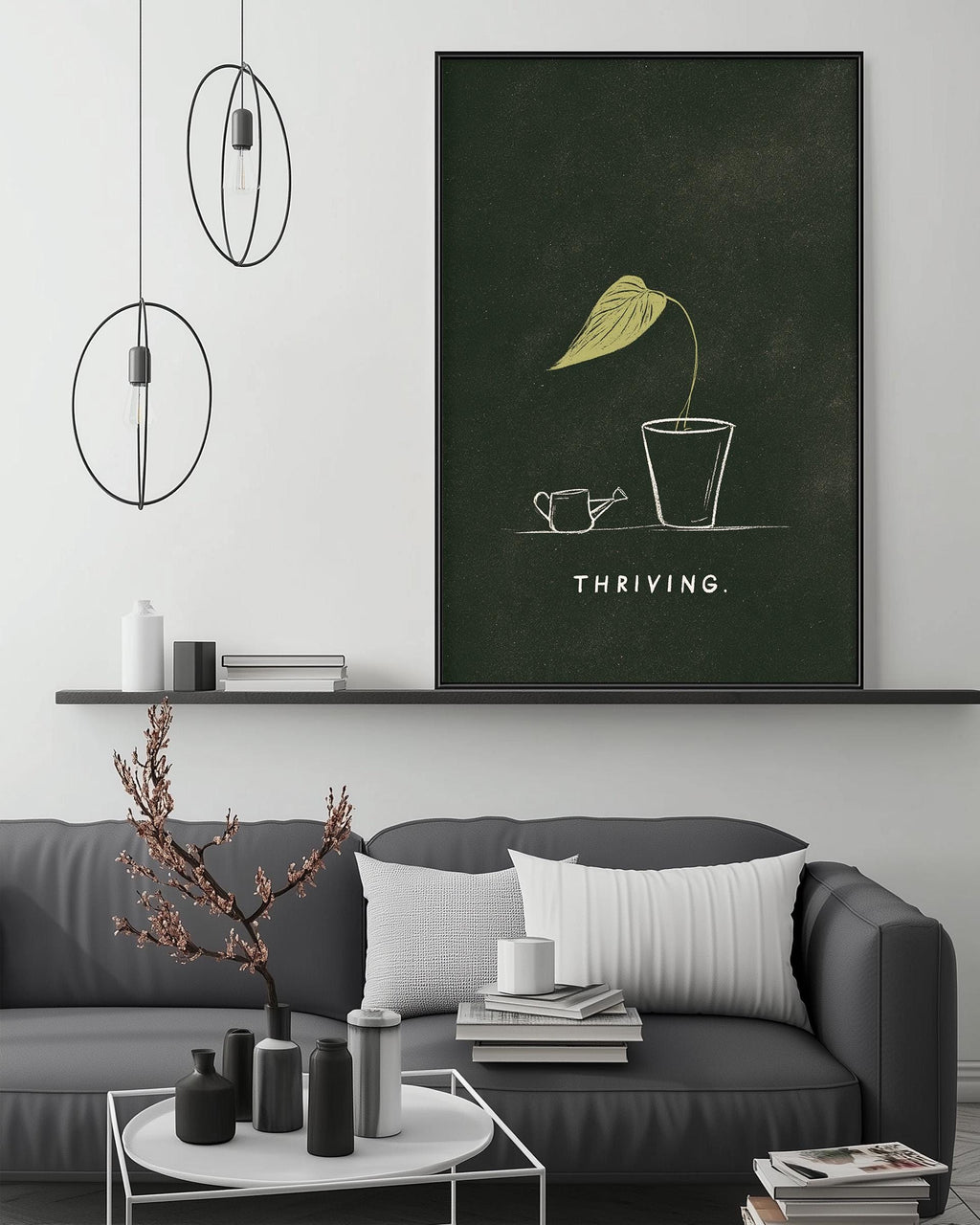 a living room with a gray sofa, a coffee table, and a large framed poster on the wall. The poster depicts a plant with a watering can, and the word "THRIVING" is written below the plant.