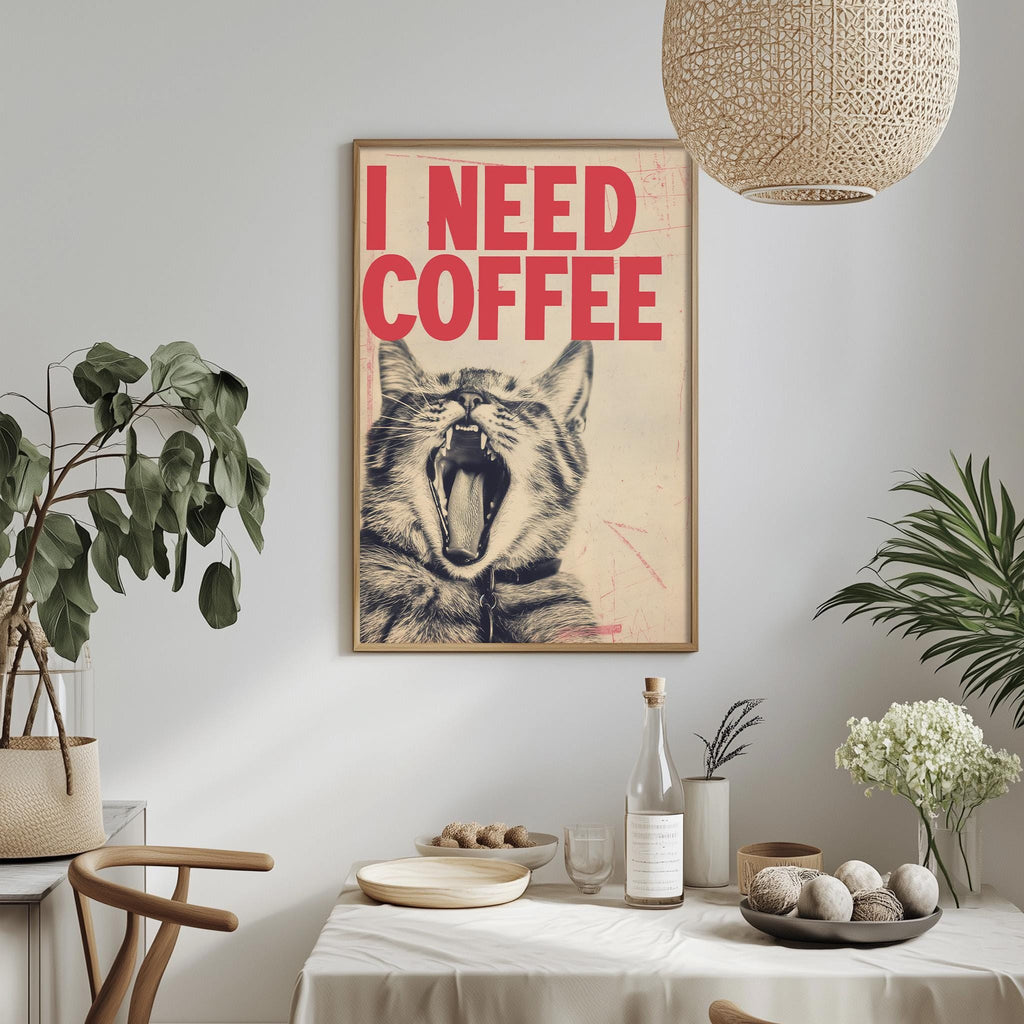 a framed poster with the text "I NEED COFFEE" hanging on a wall above a dining table with various items on it, including a bottle, a bowl, and a vase with flowers.