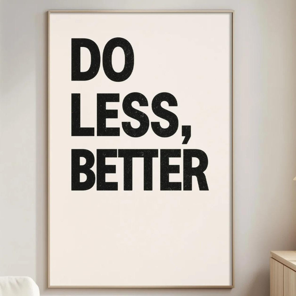 a minimalist living room with a large framed poster on the wall that reads "DO LESS, BETTER".