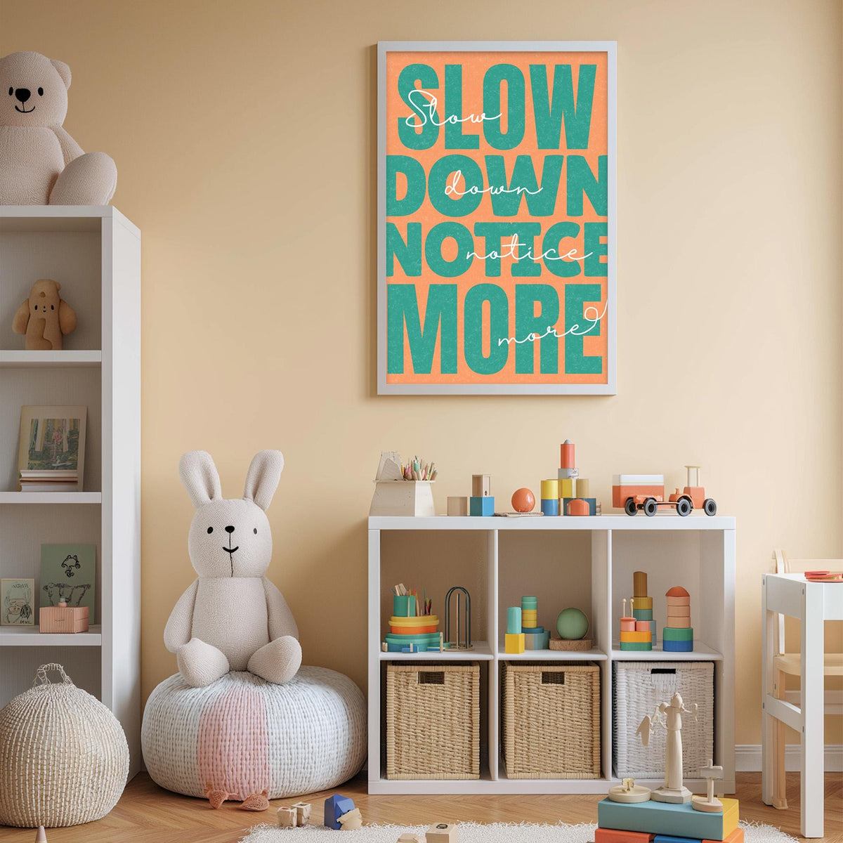 A child's bedroom with a stuffed rabbit, a bookshelf, and a toy storage unit. The wall has a framed poster with the text "Slow down, notice more" in orange and green.