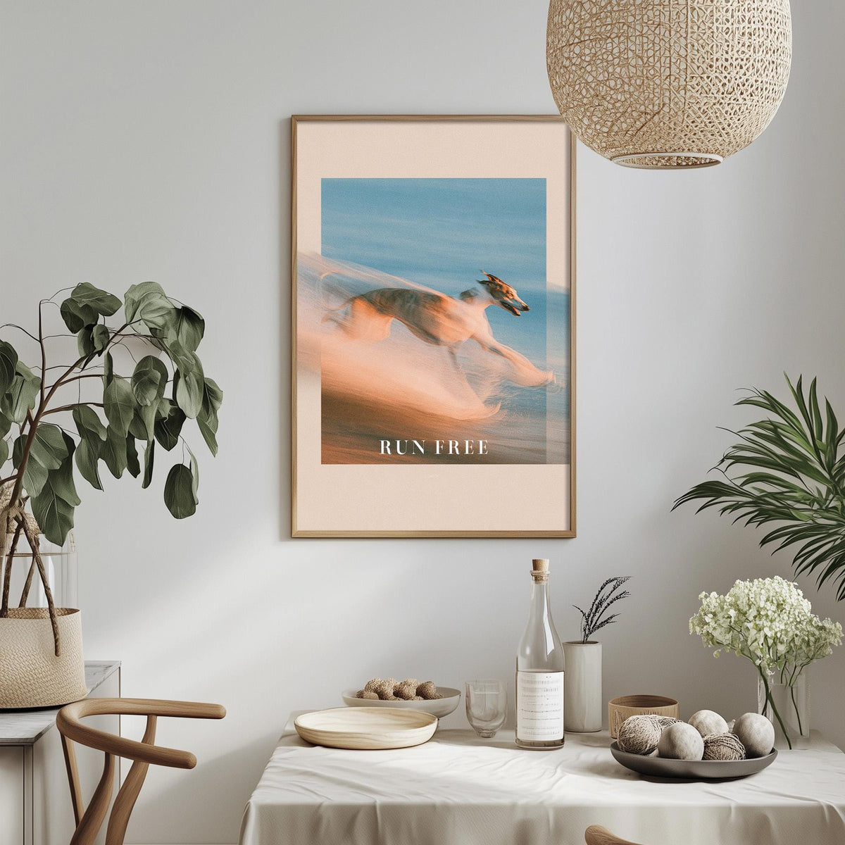 a dining table with a bowl of fruit, a bottle, and a vase of flowers, along with a framed poster of a person running.