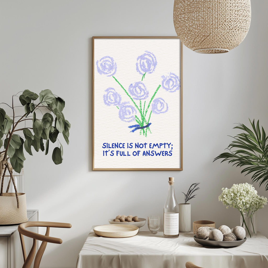a framed poster with a drawing of purple flowers and the text "Silence is not empty; it's full of answers" hanging on a wall above a dining table with various items on it.