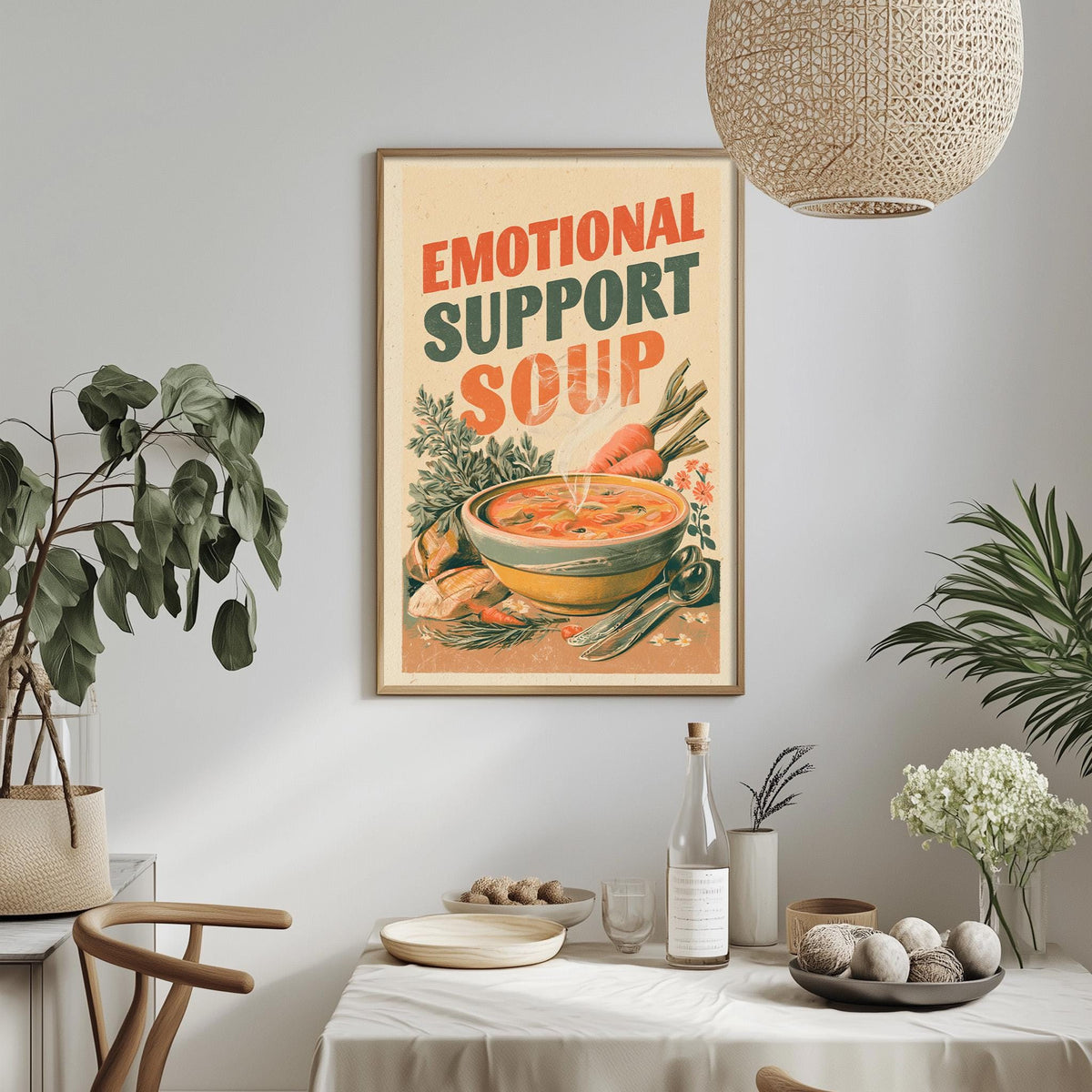 a framed poster with the text "Emotional Support Soup" hanging on a wall above a dining table with various items on it.