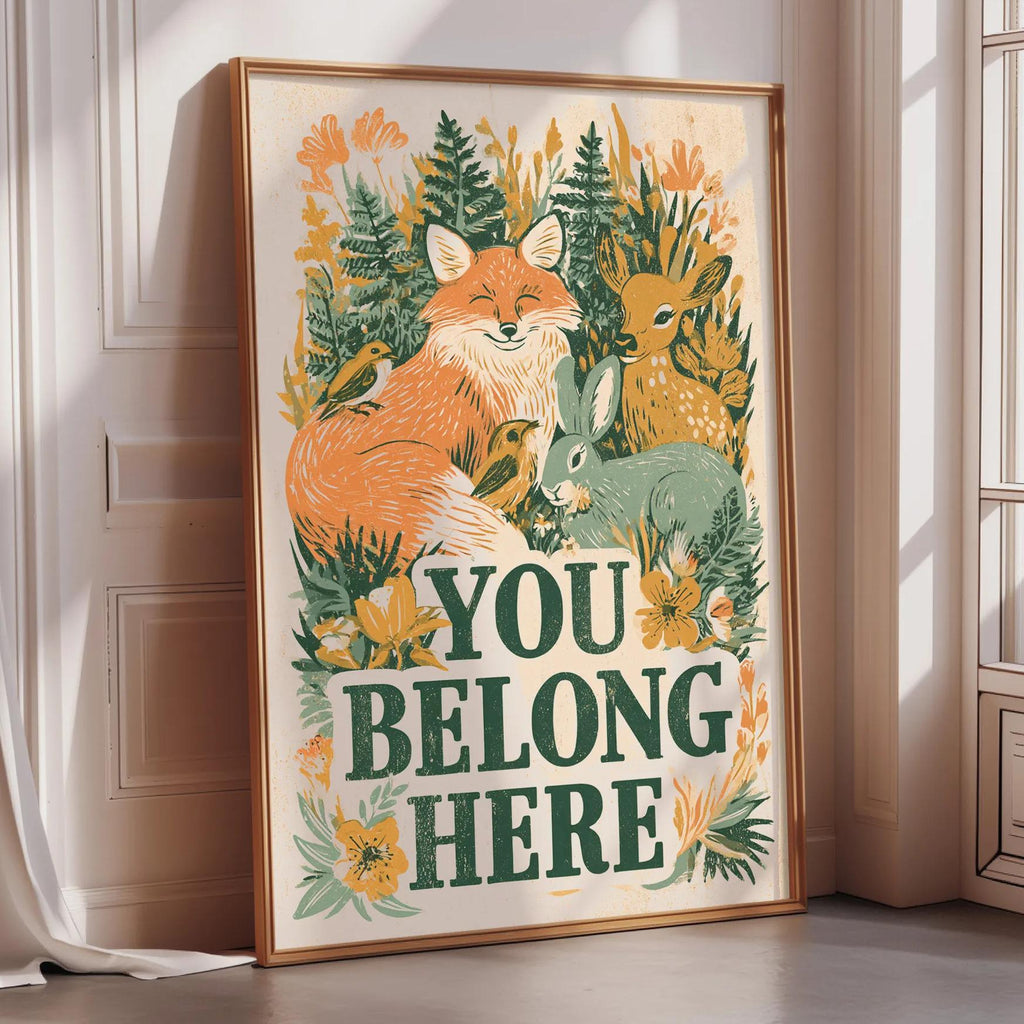 A framed poster with a vibrant illustration of animals, including a fox, rabbit, and deer, surrounded by flowers and foliage. The text on the poster reads "YOU BELLONG HERE".