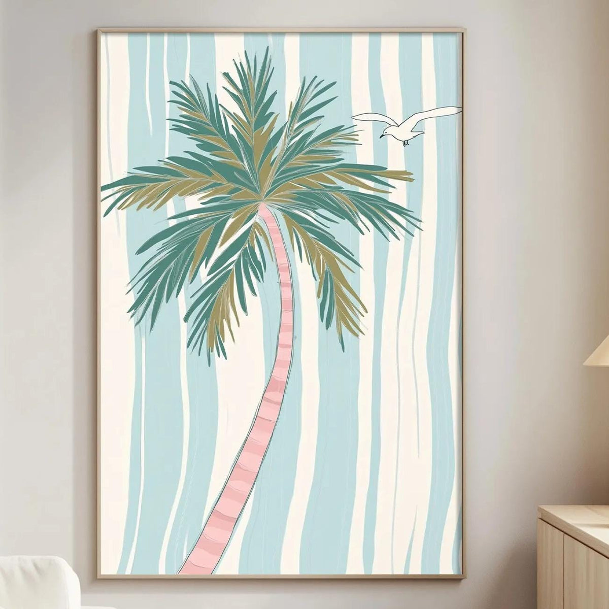 a living room with a large framed picture of a palm tree hanging on the wall. The room has a white sofa, a wooden side table, and a lamp on a nearby table.
