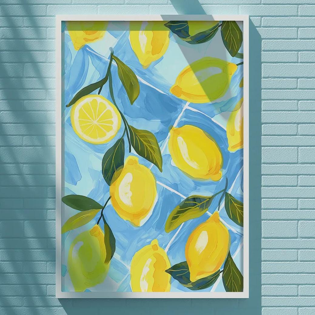 A framed painting of lemons is displayed on a blue brick wall, with a white light fixture above it.