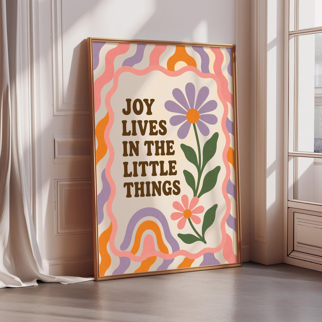A framed poster with a colorful, abstract design and text that reads "Joy lives in the little things".