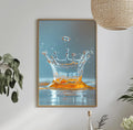 a dining table with a white tablecloth, a bowl of fruit, a bottle, and a vase with flowers. Above the table, there is a framed picture of a splash of water with an orange splash.