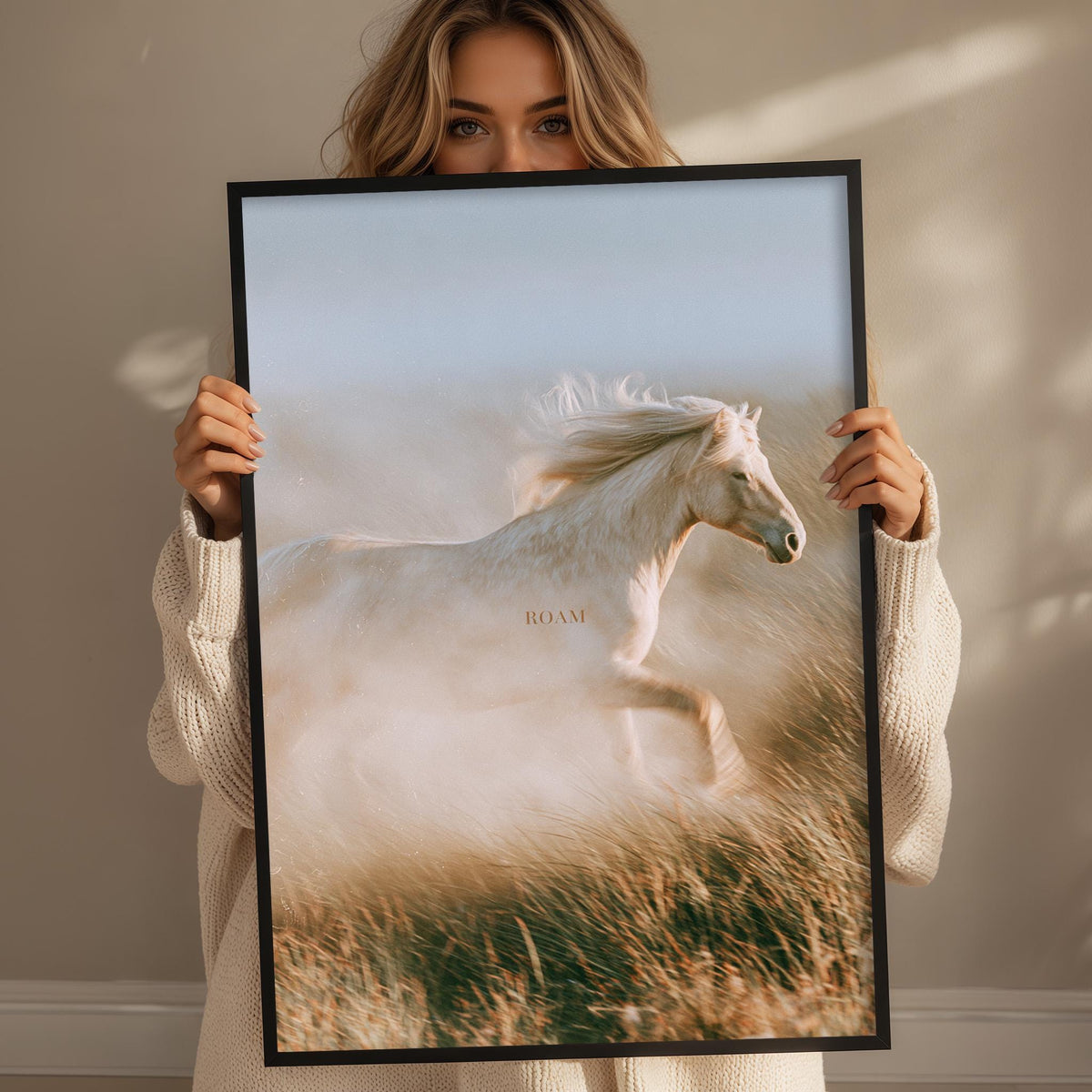 A woman holding a framed picture of a white horse running in a field.
