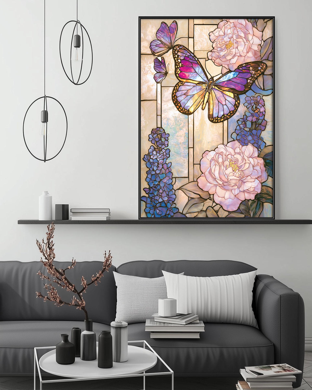 a large framed stained glass artwork depicting a butterfly surrounded by pink and purple flowers, hanging on a wall above a gray couch with a coffee table in front of it.