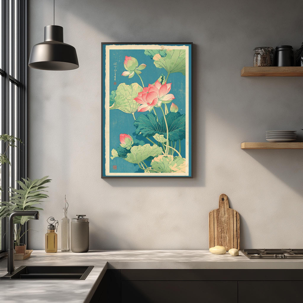 a kitchen counter with a framed print of a lotus flower and green leaves hanging on the wall above it. The counter also has various kitchen items, such as a cutting board, a bottle, and a bowl.