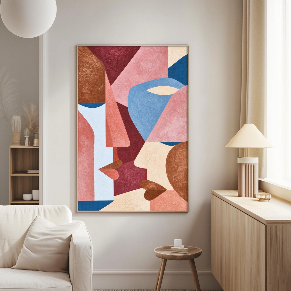a modern living room with a large abstract painting hanging on the wall. The painting is a collage of various geometric shapes in different colors, including shades of pink, blue, and orange. The room also includes a white sofa, a wooden side table, and a lamp on a wooden cabinet.
