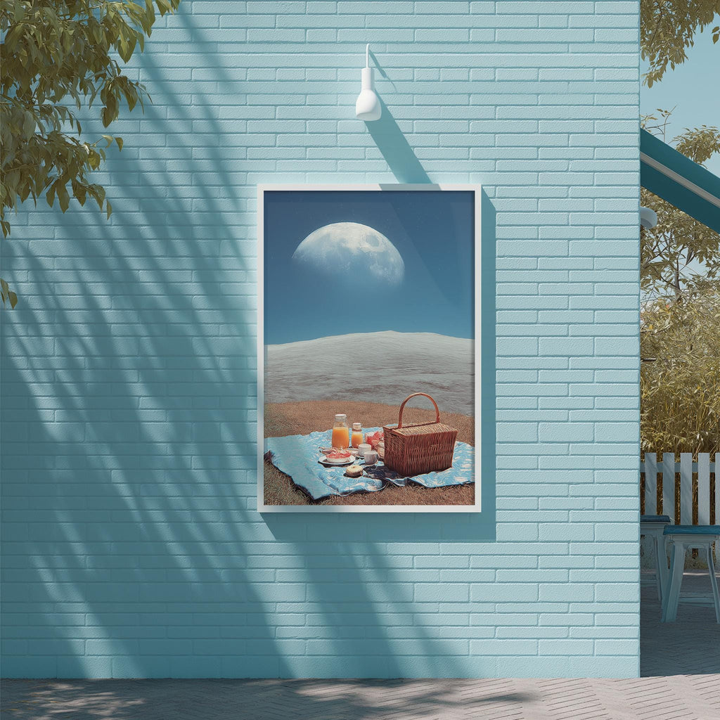 A framed image depicting a picnic scene with a basket, orange juice, and a beach in the background, set against a blue brick wall.