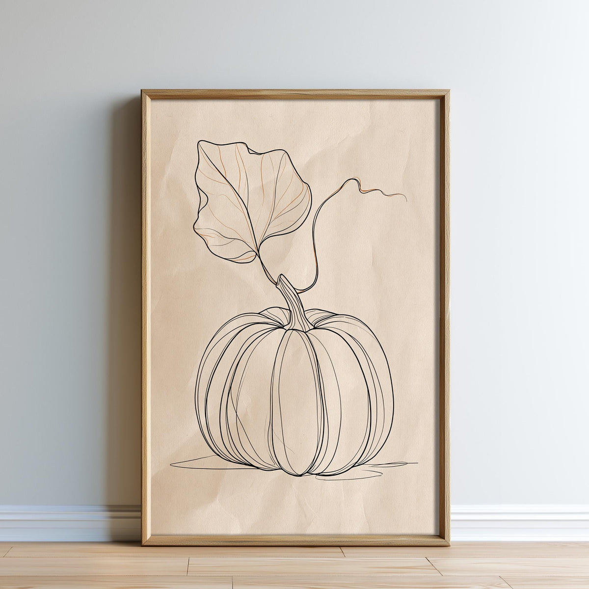 A framed print of a pumpkin with a leaf attached to it, displayed on a wall.
