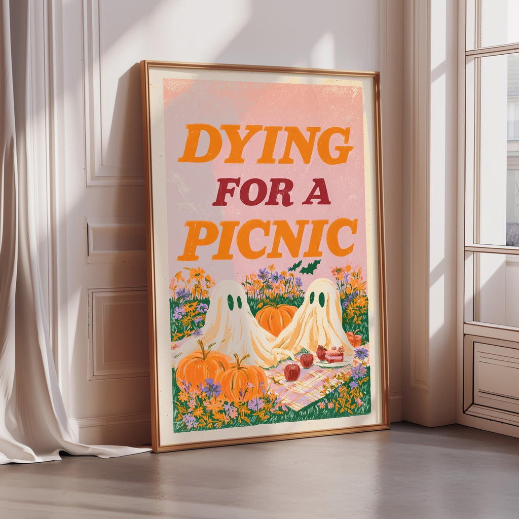 a framed poster with a Halloween-themed illustration, including two ghostly figures, pumpkins, and a picnic scene.