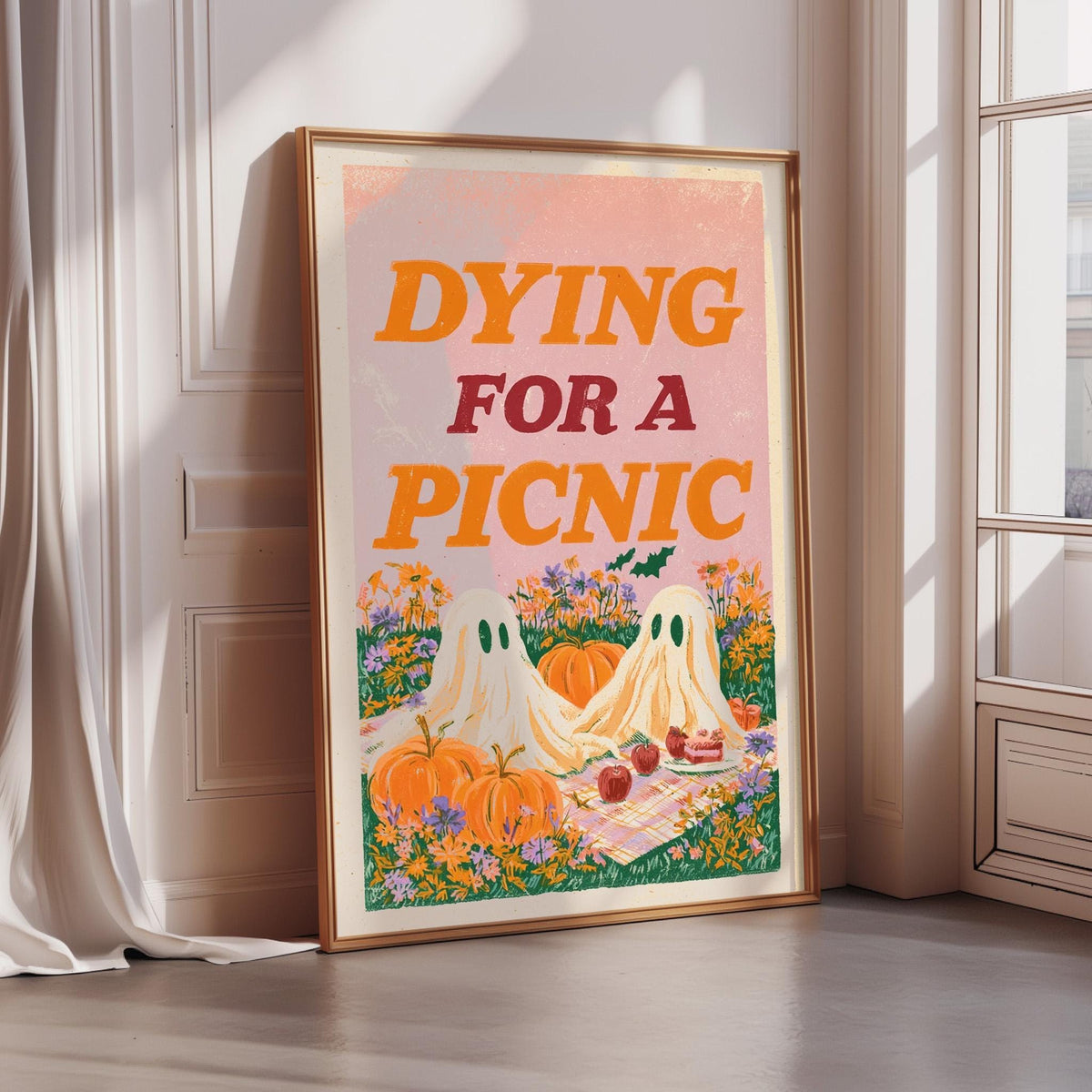 a framed poster with a Halloween-themed illustration, including two ghostly figures, pumpkins, and a picnic scene.