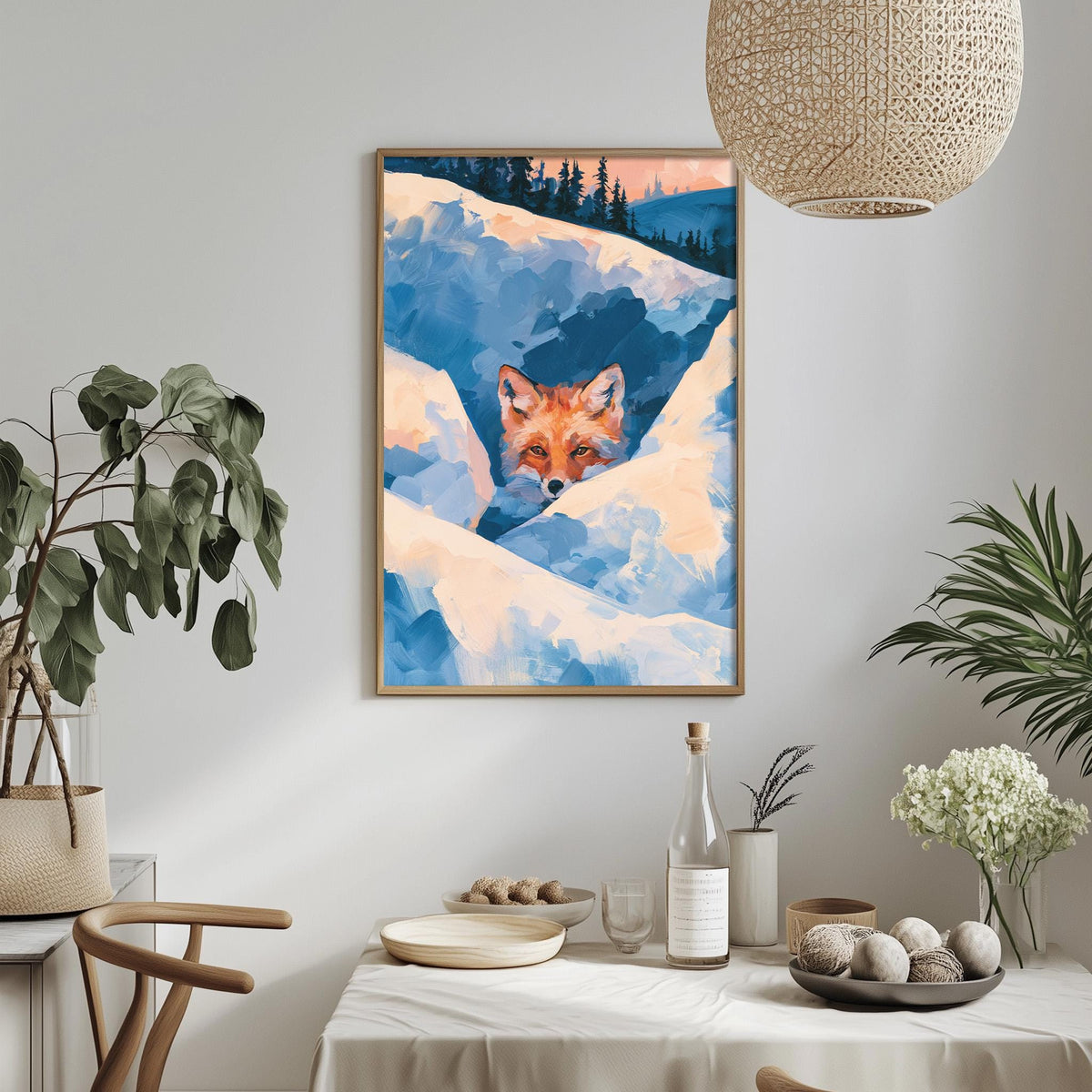 a framed painting of a fox peeking out from behind a snowy landscape, hanging on a wall above a dining table with various decorative items and plants.