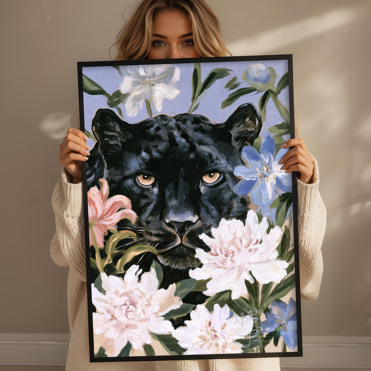 A woman holds up a framed painting of a black panther surrounded by colorful flowers.