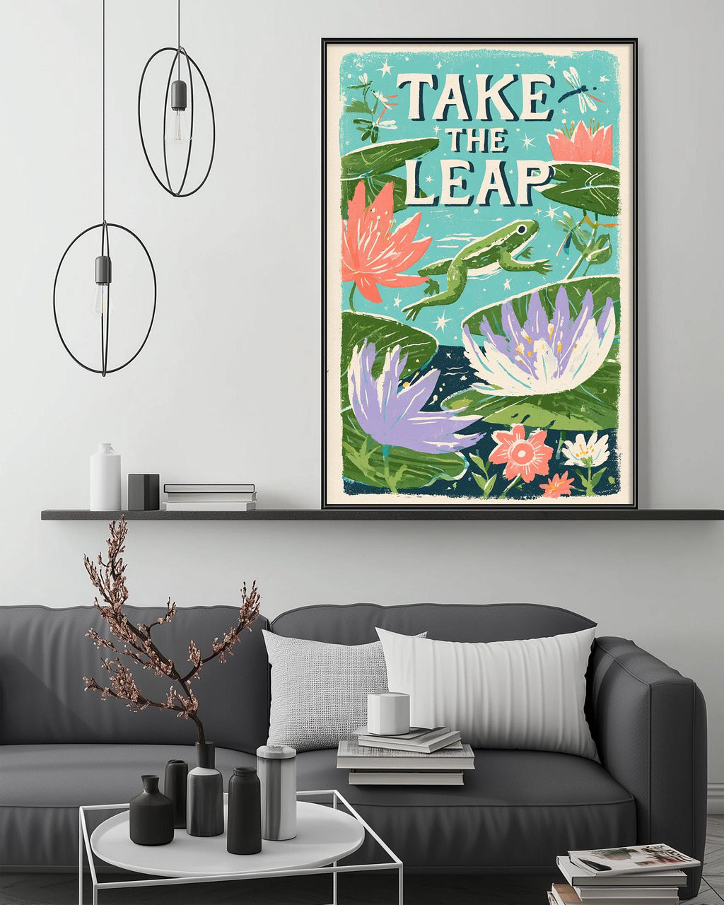 a large framed poster with a vibrant illustration of a frog leaping over a pond filled with colorful flowers, hanging on a wall above a gray couch in a living room setting.