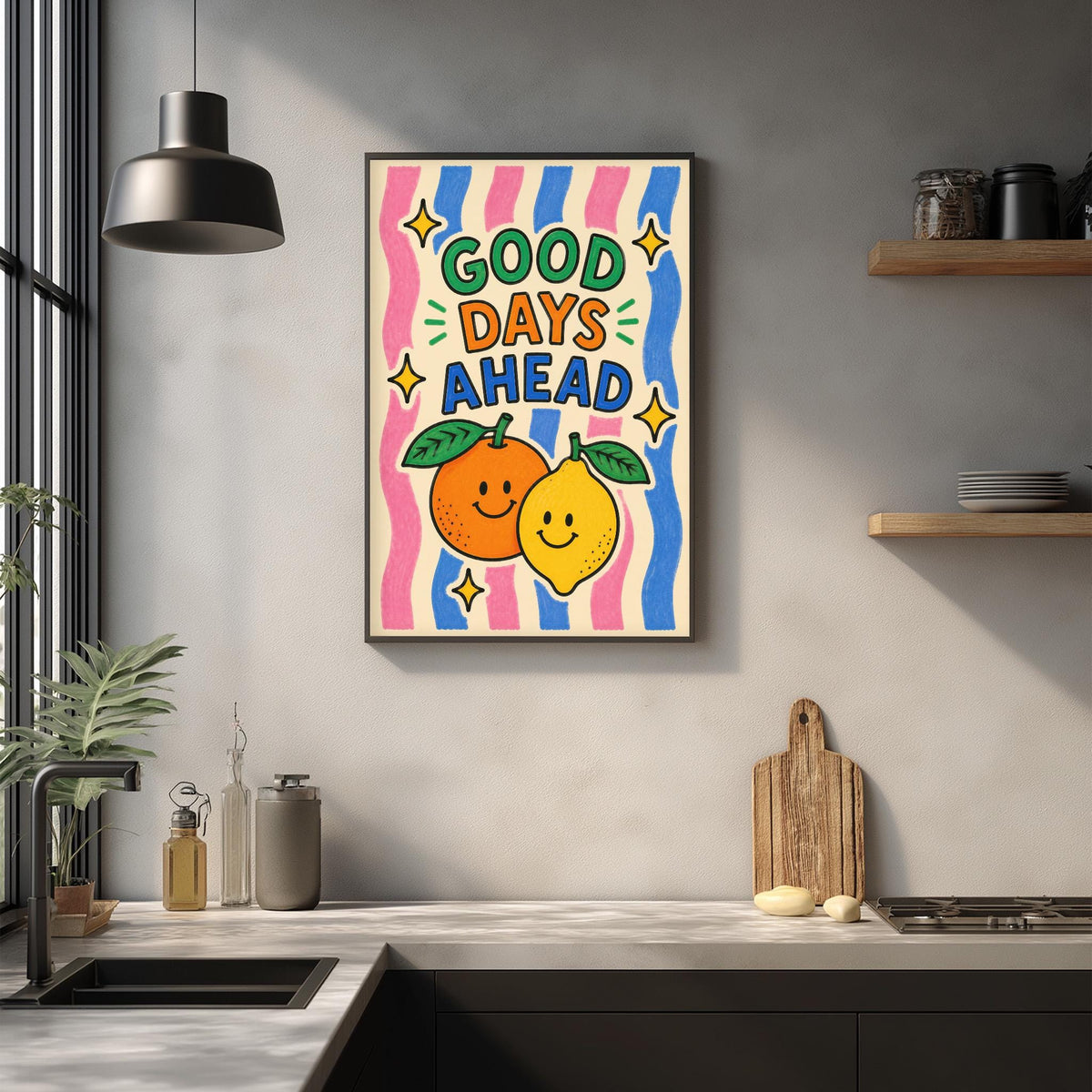 a kitchen counter with a framed poster hanging on the wall above it. The poster has a colorful design with illustrations of two smiling fruits, an orange and a lemon, along with the text "GOOD DAYS AHEAD".