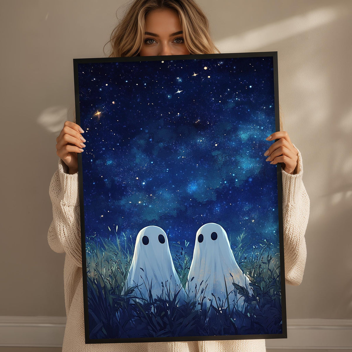 A woman holds up a framed poster depicting two ghostly figures standing in a field under a starry night sky.
