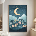 a cozy living room with a large framed poster of a nighttime village scene hanging on the wall. The poster depicts a village with houses and trees under a crescent moon and starry sky, creating a serene and peaceful atmosphere.