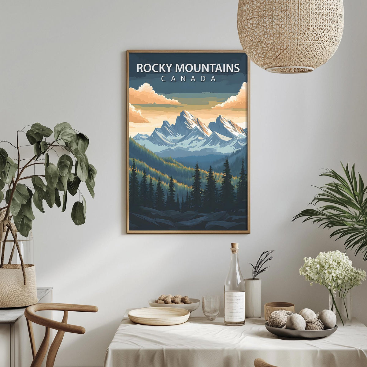 a framed poster of Rocky Mountains Canada hanging on a wall, with a dining table and chairs in the foreground.