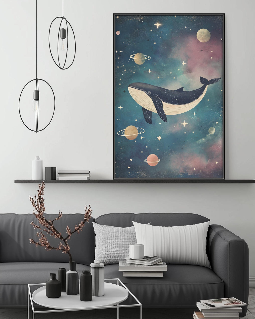 a large, colorful painting of a whale floating in a starry, cosmic-themed space above a gray couch with white pillows. The painting is hanging on a wall, and there are two black pendant lights hanging from the ceiling above the couch. The couch is positioned in front of a coffee table with various decorative items, such as a small tree, a vase, and a stack of books.