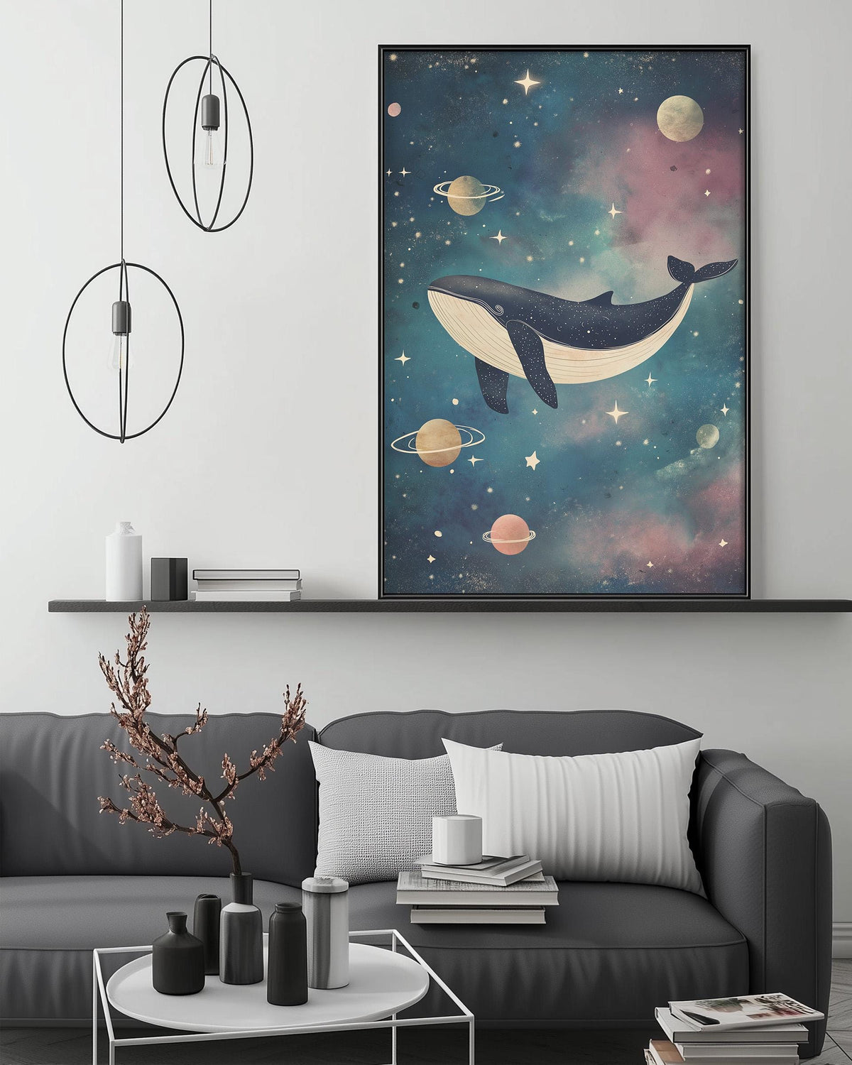 a large, colorful painting of a whale floating in a starry, cosmic-themed space above a gray couch with white pillows. The painting is hanging on a wall, and there are two black pendant lights hanging from the ceiling above the couch. The couch is positioned in front of a coffee table with various decorative items, such as a small tree, a vase, and a stack of books.