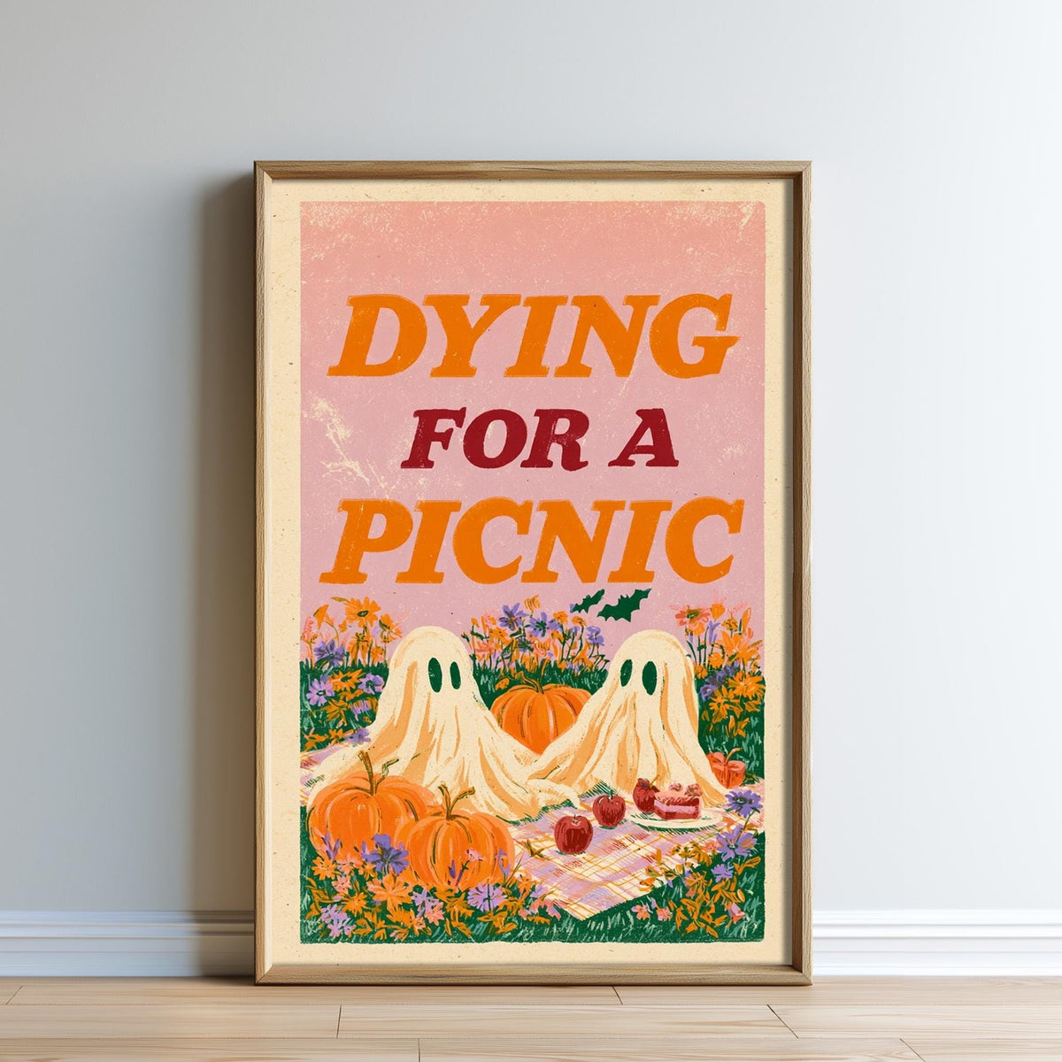 The image is a framed poster with a Halloween-themed illustration. It features two ghostly figures sitting on a picnic blanket, surrounded by pumpkins, flowers, and a cake. The text on the poster reads " Dying for a Picnic".