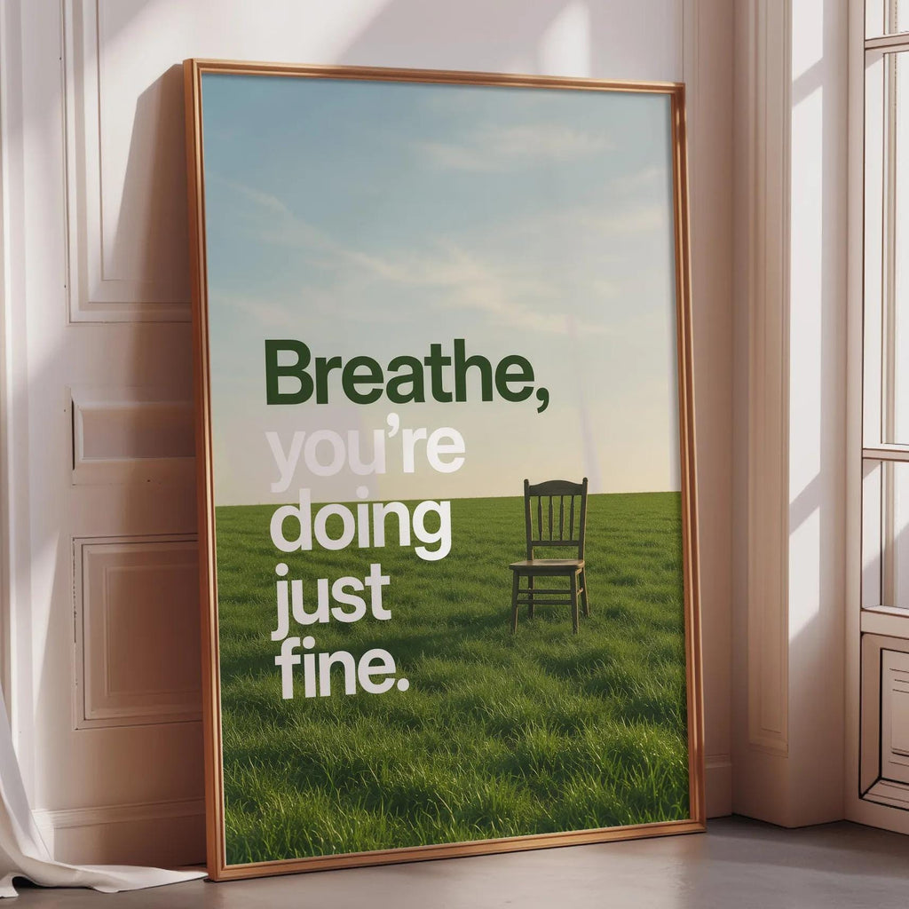a large framed poster with a serene landscape of a grassy field and a solitary chair, accompanied by the text "Breathe, you're doing just fine."